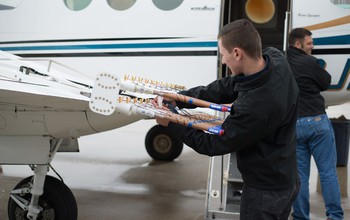 Pilots from Weather Modification, Inc., prepare the cloud seeding aircraft with seeding flares.